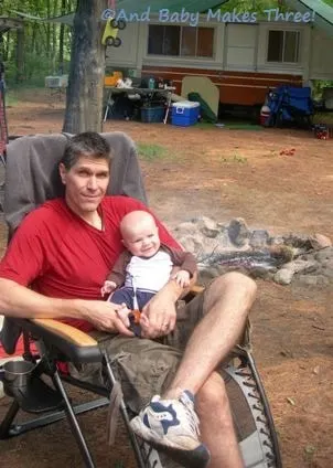 A man sitting on a chair camping with a baby