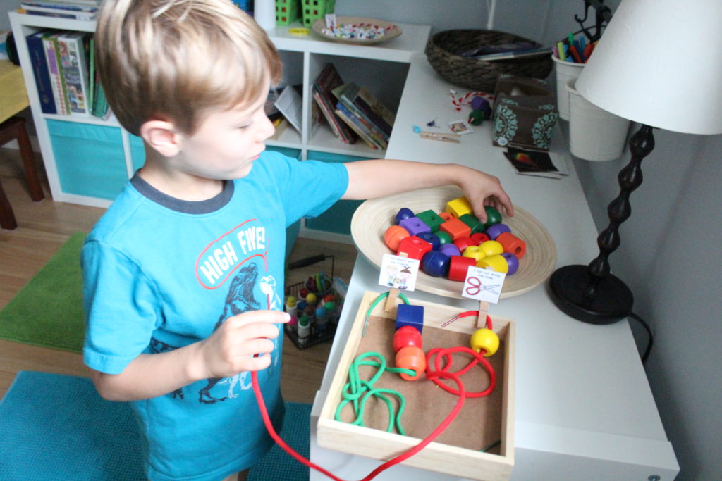 overhead shot of child selecting a large wooden bead from a tray