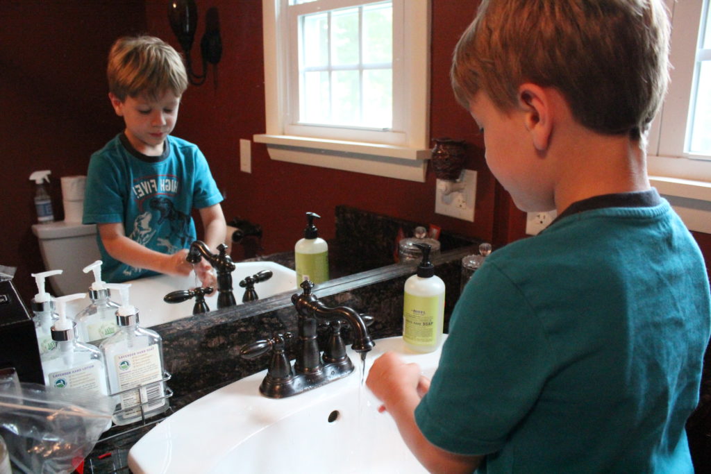 child washing hands in bathroom