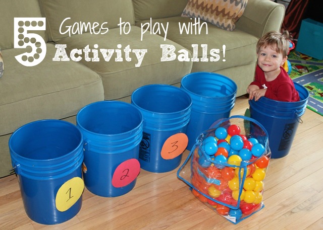 Child in bucket with other buckets and plastic balls on floor