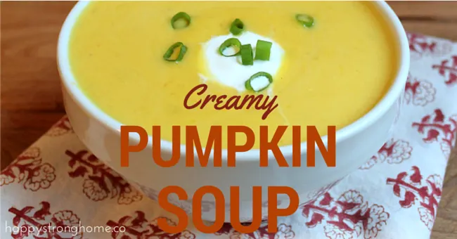 Creamy pumpkin soup on table