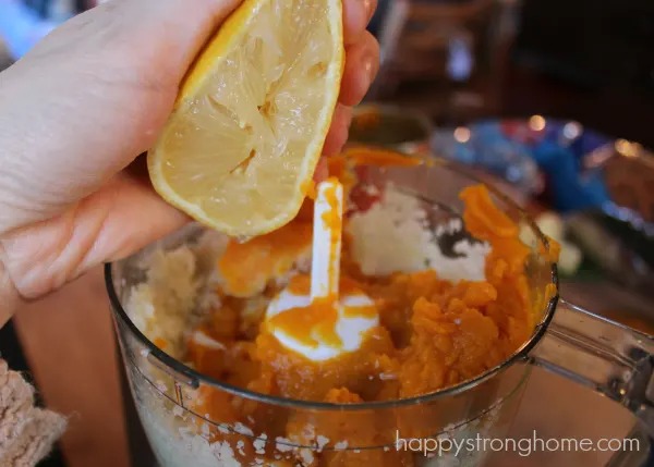 lemon juice being squeezed into blender of pumpkin