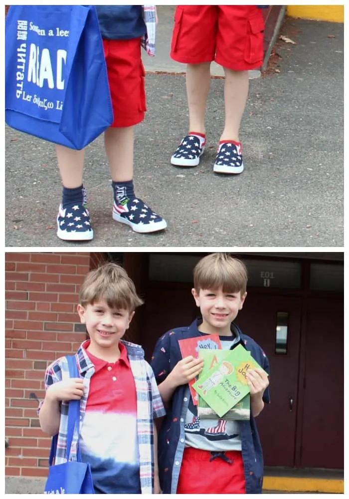 two children standing next to a building holding books