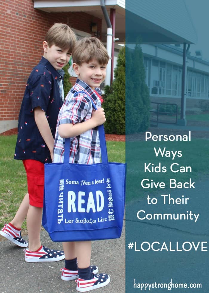 two children on  a sidewalk next to a building holding a bag