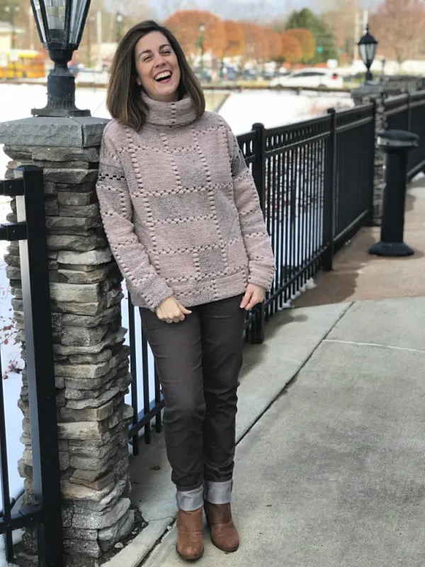 A woman wearing a pink sweater standing on a sidewalk