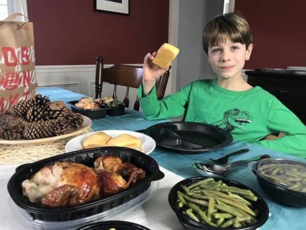 A boy sitting at a table with a plate of food