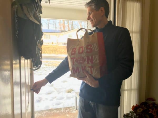 A man opening a door holding a delivery bag of food