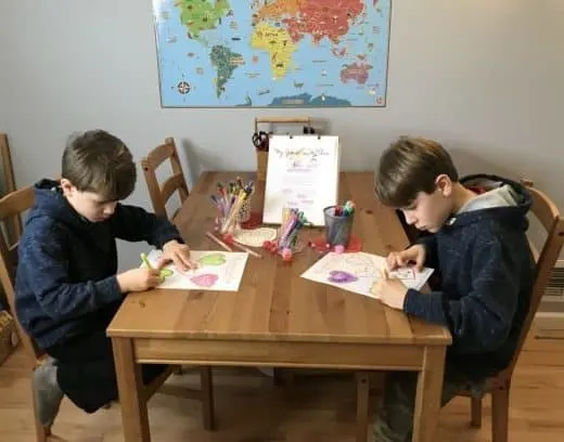 A group of people sitting at a table, coloring a Valentine\'s worksheet