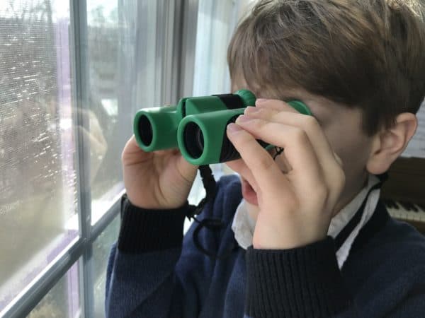 Boy with binoculars looking out window