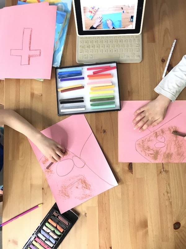 Close up of Children\'s hands drawing with chalk pastels on pink paper