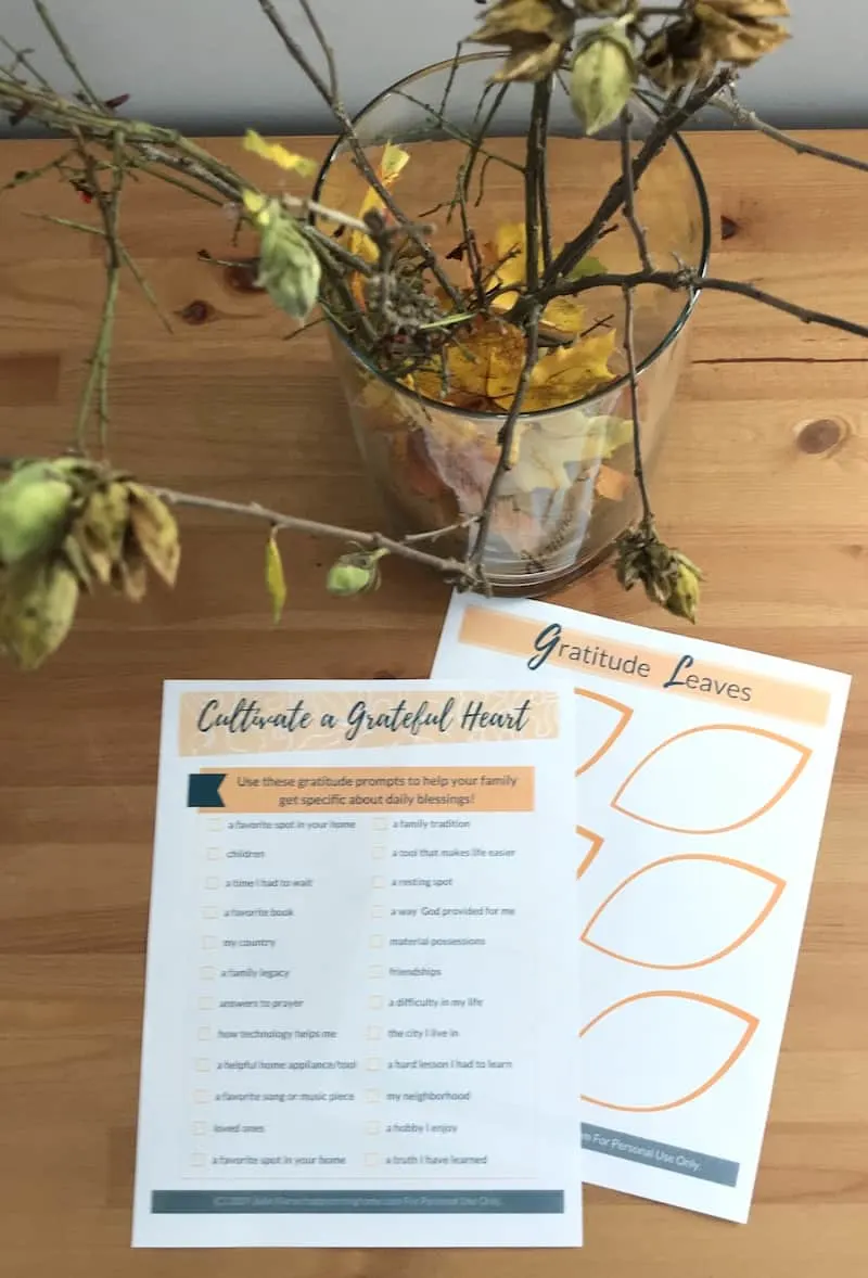 Two pages of printable gratitude prompts for Thanksgiving on a table with branches in a vase