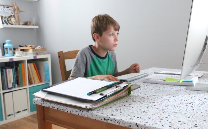 A young student sitting at a table looking at something 