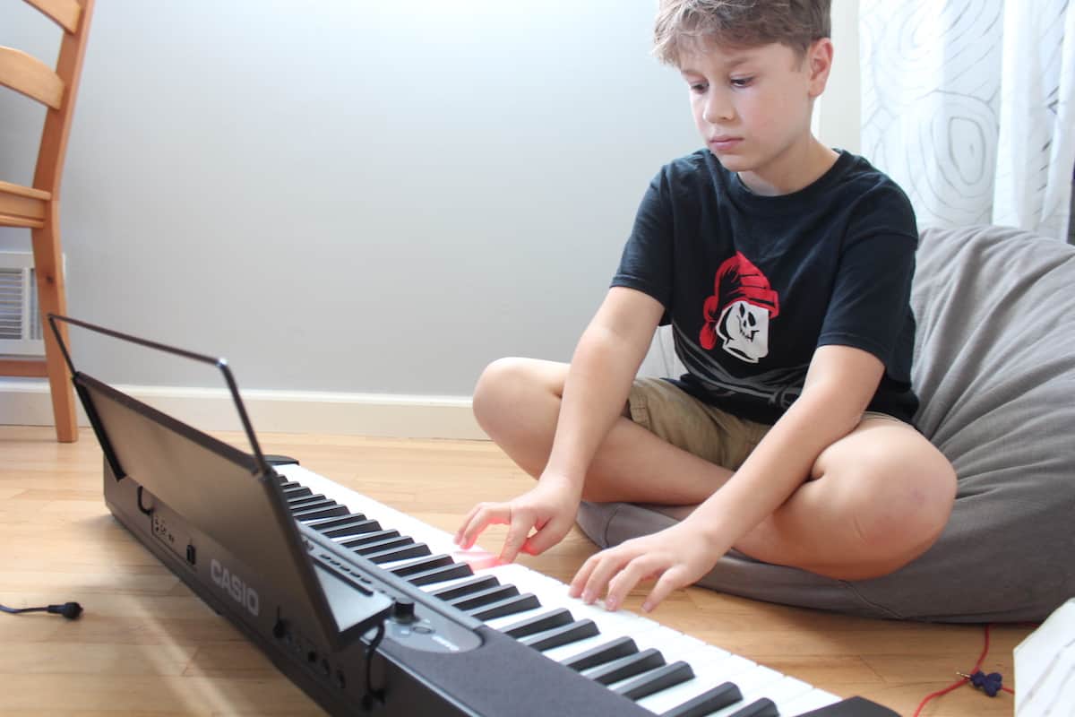 kid playing piano keyboard on floor