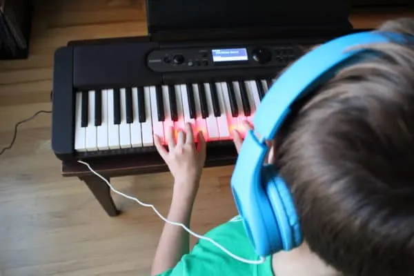 over shoulder view of piano player wearing headphones with hands on keyboard