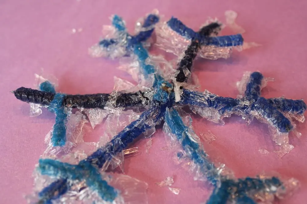 close up of blue pipe cleaner snow crystal shape covered in salt crystals