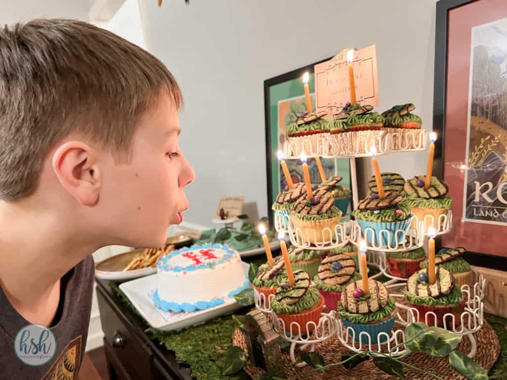 child blowing out beeswax birthday candles on hobbit hole cupcakes