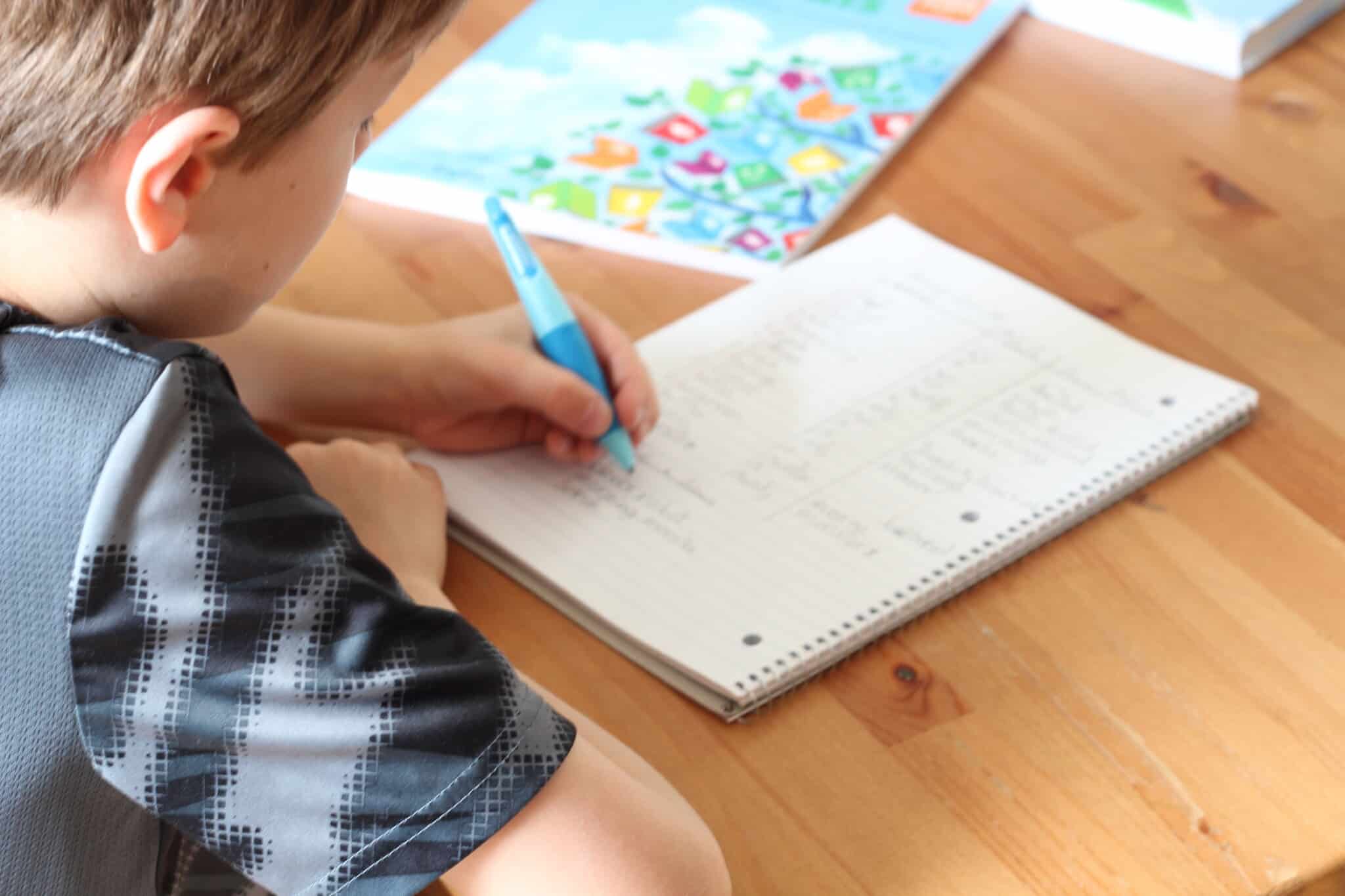 student writing in notebook at a table, Teaching writing at home can happen anywhere