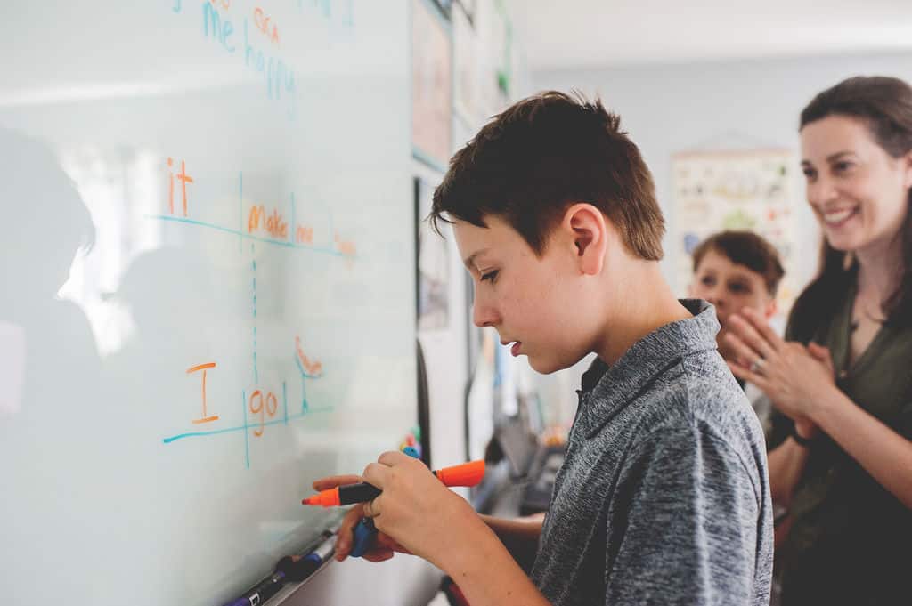 parent edits child's writing on whiteboard
